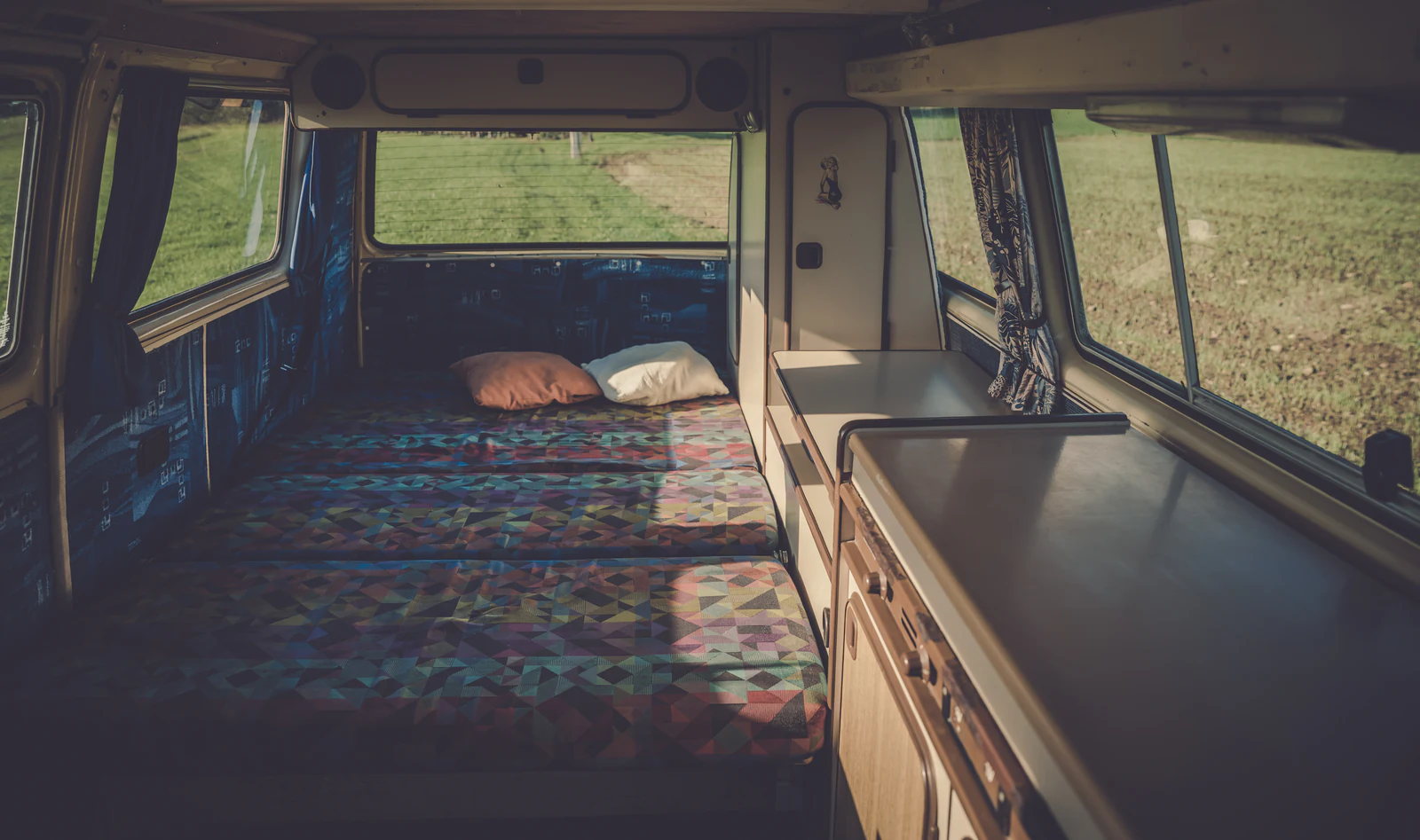 Interior camperizado de una furgoneta con cama, mueble y encimera